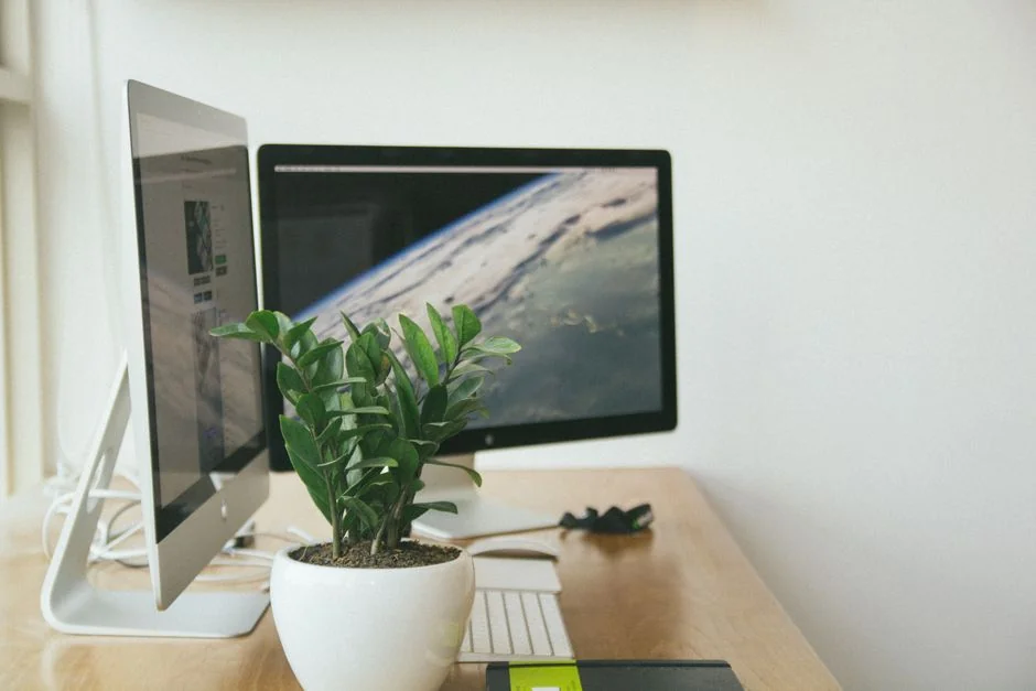 A minimalist desk setup featuring dual monitors, keyboard, mouse, and notebook for productivity.